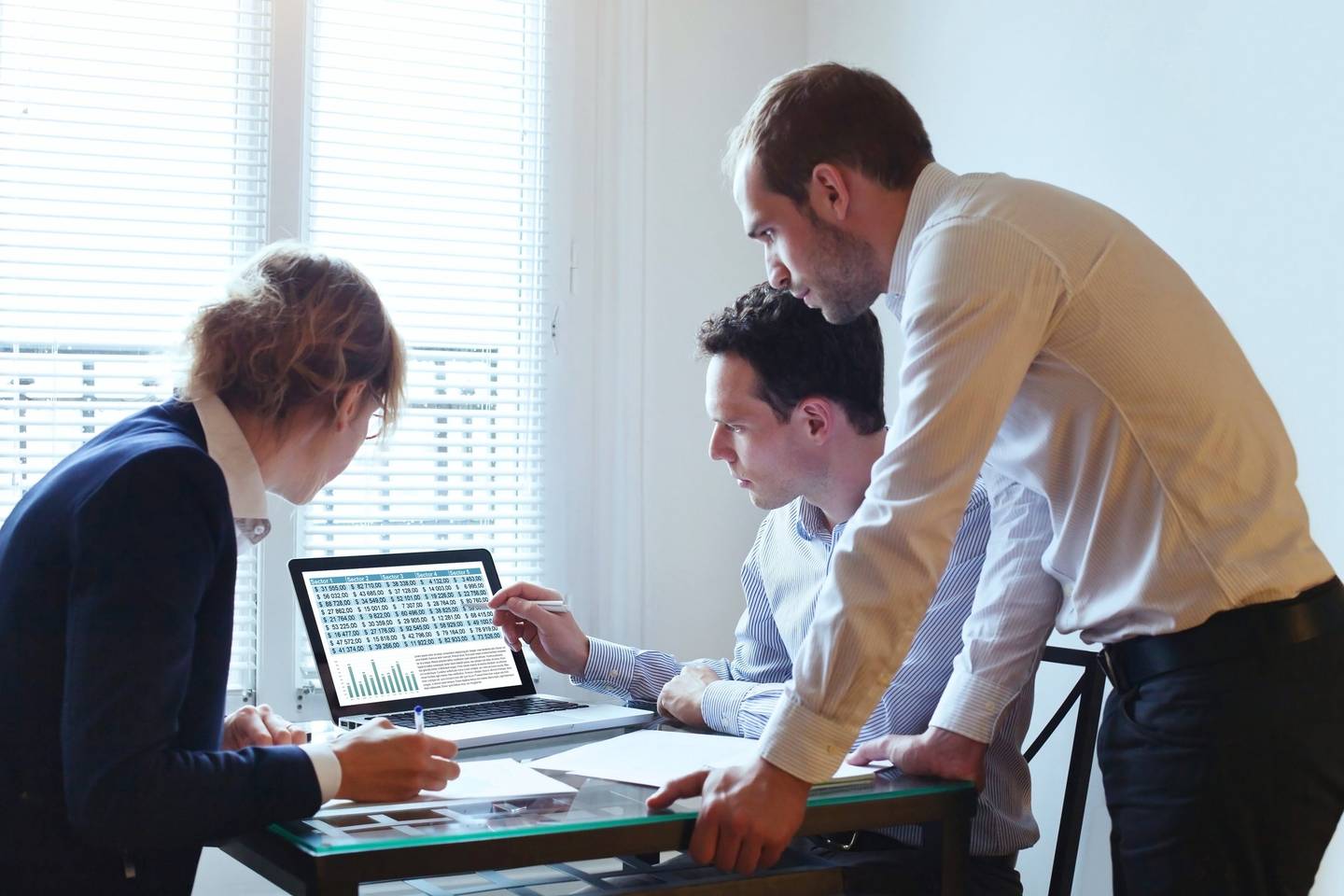Three people looking at data on a laptop