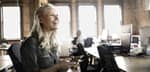 Businesswoman with cell phone laughing in office( 1)