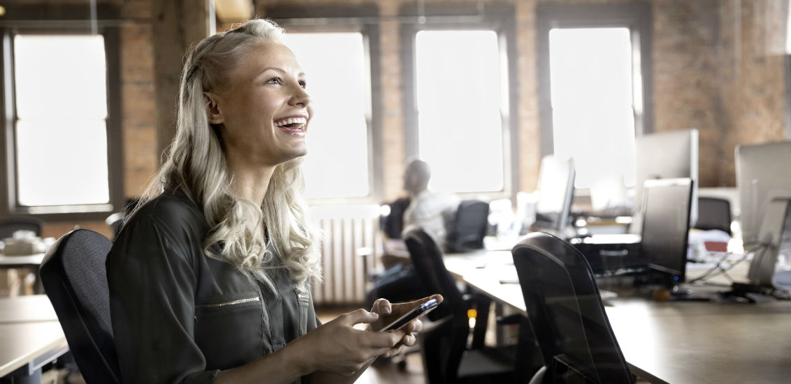 Businesswoman with cell phone laughing in office( 1)