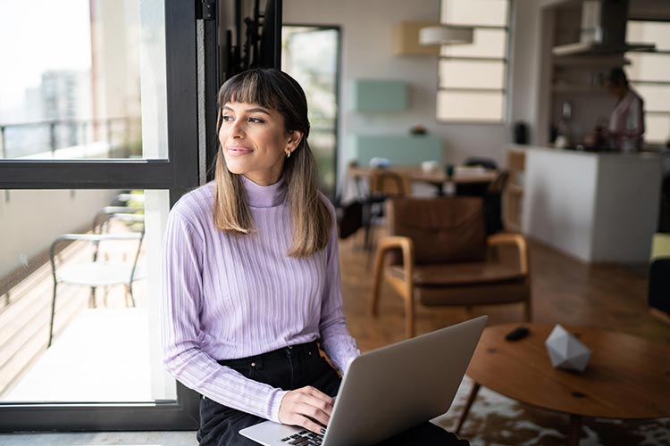 Woman Sitting By Window With Laptop 750 x 500