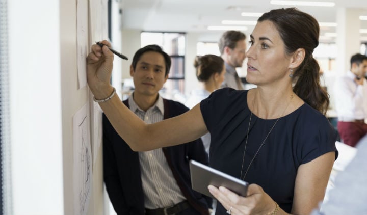 Businesswoman writing at wall 720 x 422