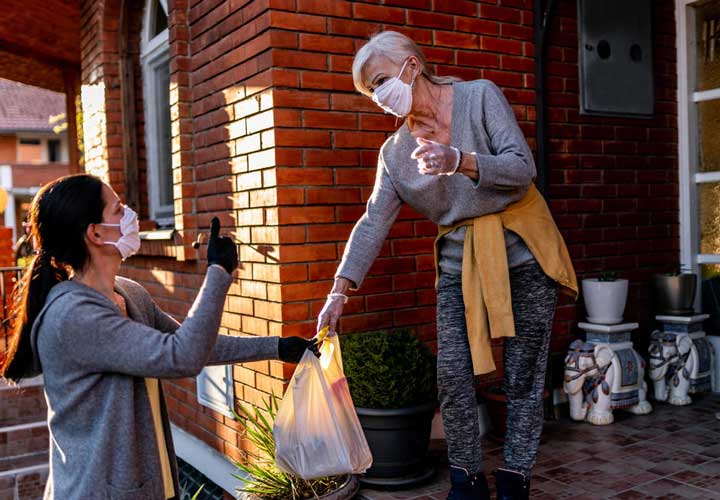 Volunteer Bringing Groceries To A Senior Woman 720x500