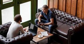 Two Men With Laptop Sitting On Couch Lounge meta 560x292